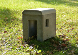 Skulptur von einem Bauwagen aus Beton in kleinem Format. Die Skluptur steht auf der Wiese.