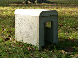 Skulptur von einem Bauwagen aus Beton in kleinem Format. Die Skluptur steht auf der Wiese.