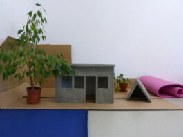 Ausstellung mit Miniaturhäusern aus Beton, Pflanzen, Pappen und Isomatten