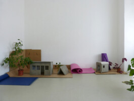 Ausstellung mit Miniaturhäusern aus Beton, Pflanzen, Pappen und Isomatten